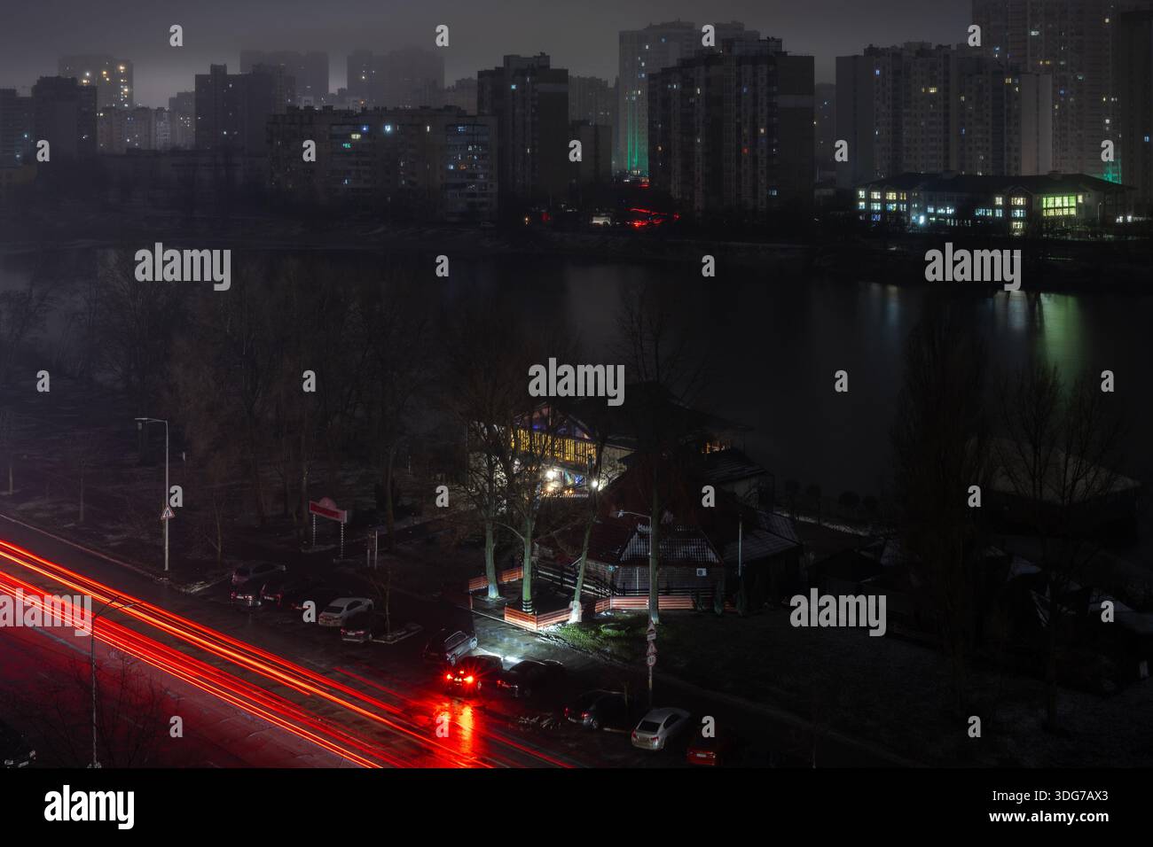 Kiev, Ucraina – 16 gennaio 2023: Colpo ad angolo alto di via Kyiv, vicino al lago Sonyachne. Il semaforo rosso passa dal traffico automobilistico, edifici bui senza eleggere Foto Stock