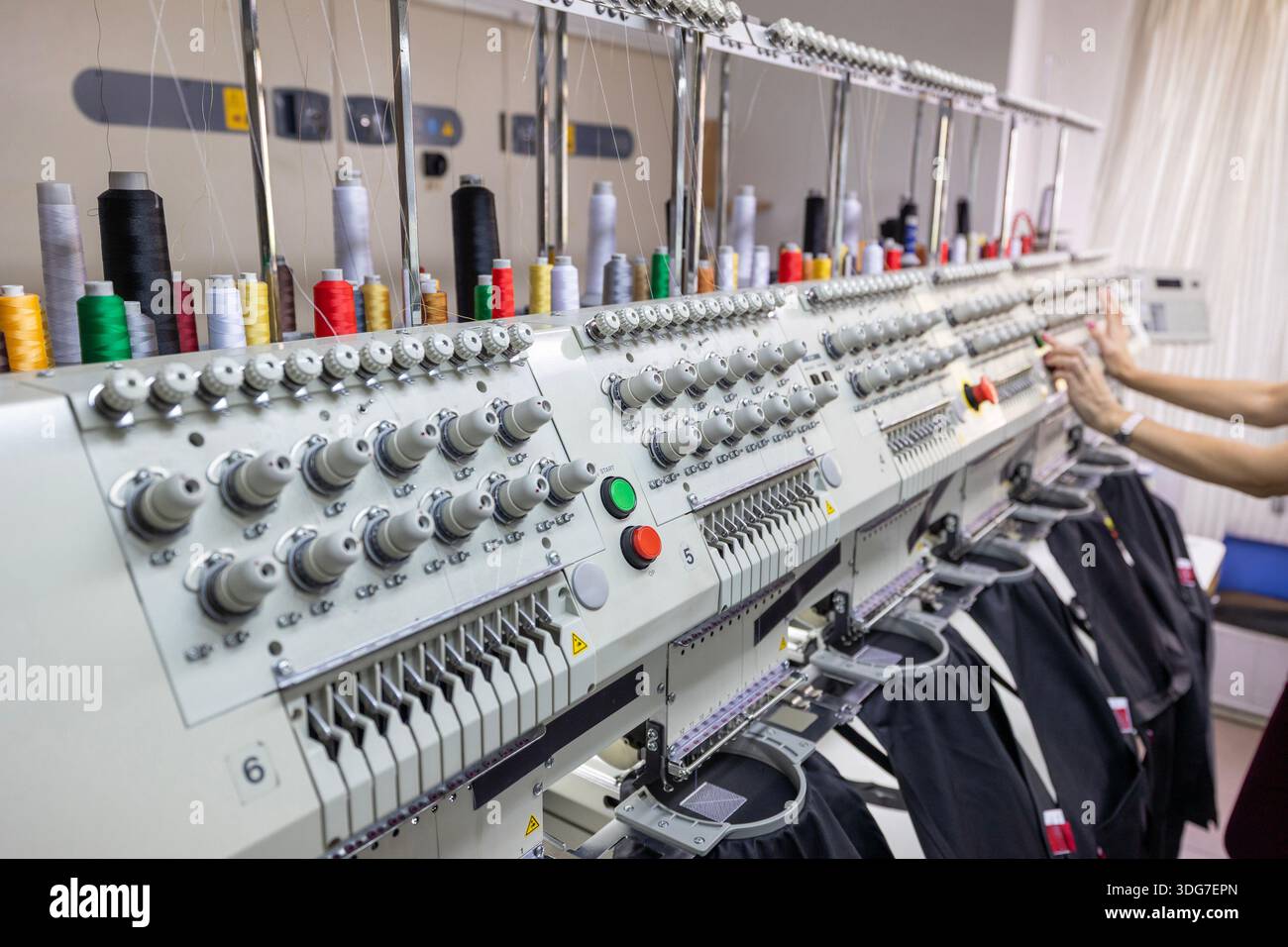 Teste per macchine da ricamo professionali con cuciture in tessuto nero. Processo automatizzato di branding delle uniformi del personale di ristorante e degli abiti da lavoro da cucina utilizzando multi Foto Stock
