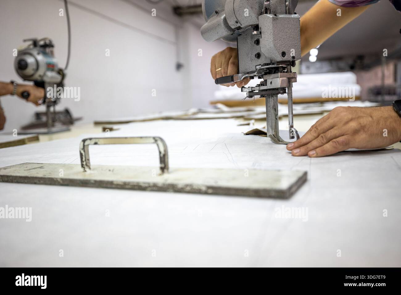 Taglierina elettrica industriale per tessuto da taglio per uniforme militare. Primo piano di attrezzature professionali per la fabbrica di cucito per il taglio di tessuti ad alta precisione f Foto Stock