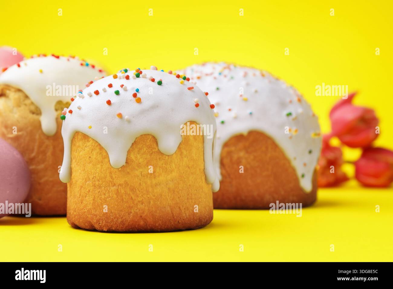 Deliziose torte di Pasqua e tulipani su sfondo giallo, primo piano Foto Stock