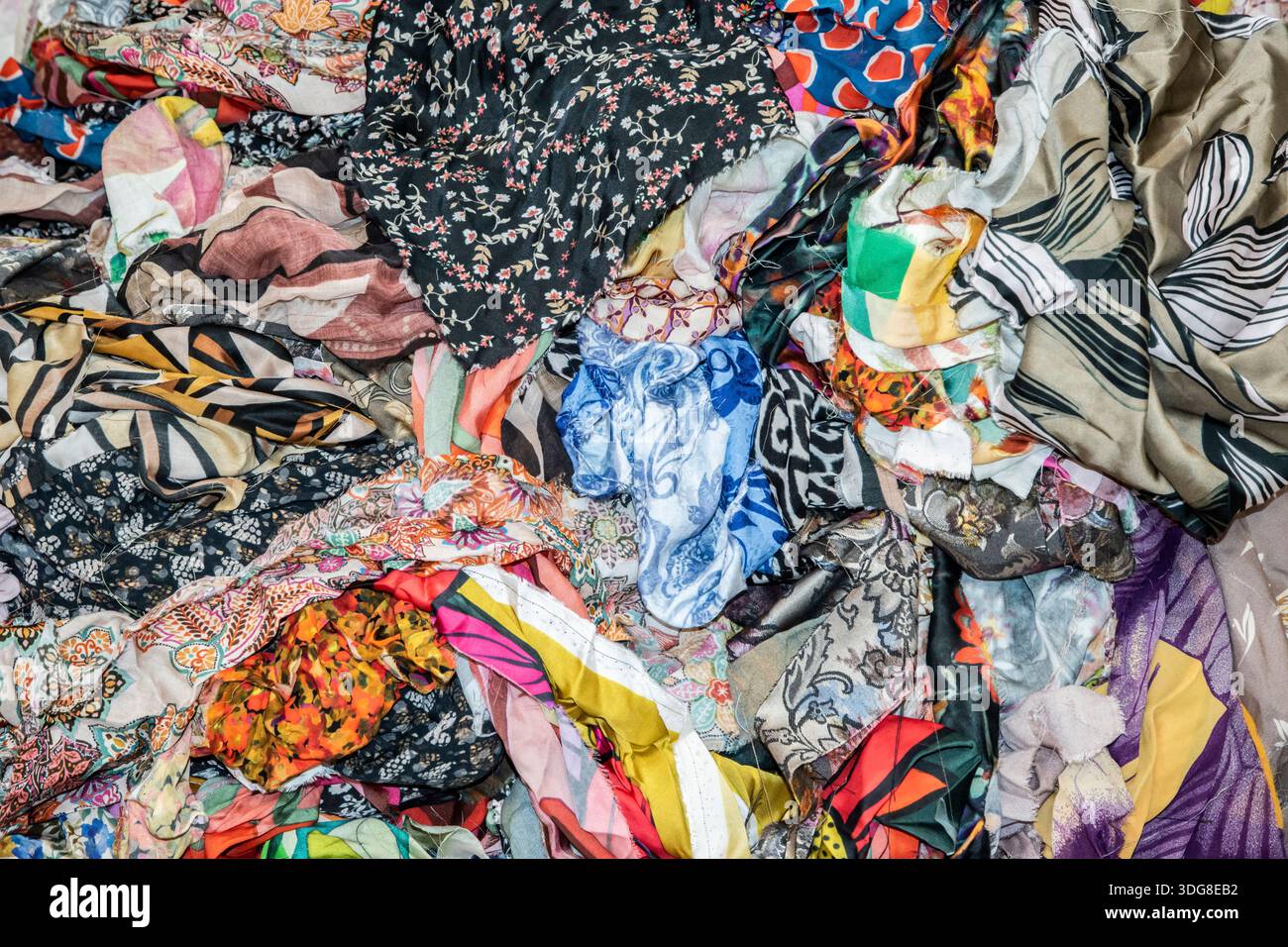 Primo piano di frammenti di tessuto colorati misti in uno studio di moda, simboleggiando il design tessile, il riutilizzo, la creatività e la produzione di abbigliamento sostenibile. Foto Stock