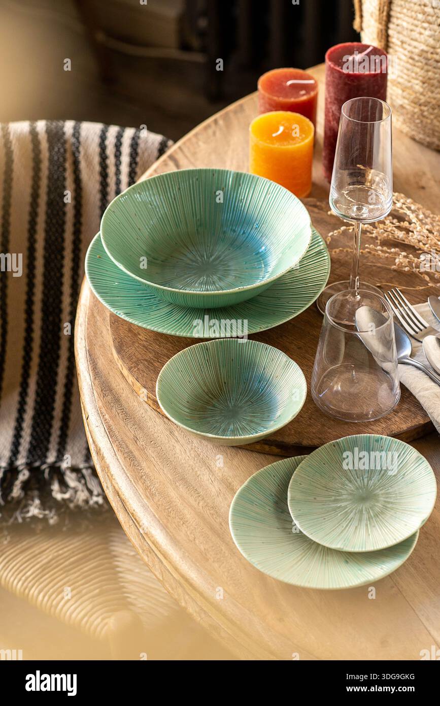 Un sofisticato ambiente da tavolo caratterizzato da un set di ciotole e piatti in ceramica verde smeraldo con una texture radiale unica al sole. Foto Stock
