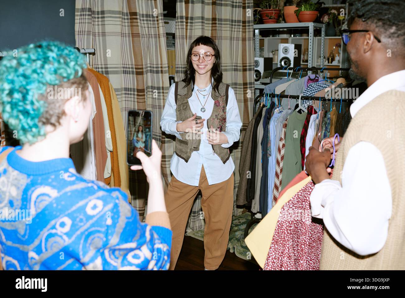 Giovane donna caucasica sorridente mentre prova i vestiti in Second Hand Store Foto Stock