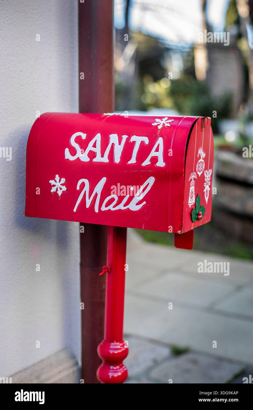 Incantevole cassetta postale di Natale rossa con fiocchi di neve e decorazioni natalizie all'aperto. Foto Stock
