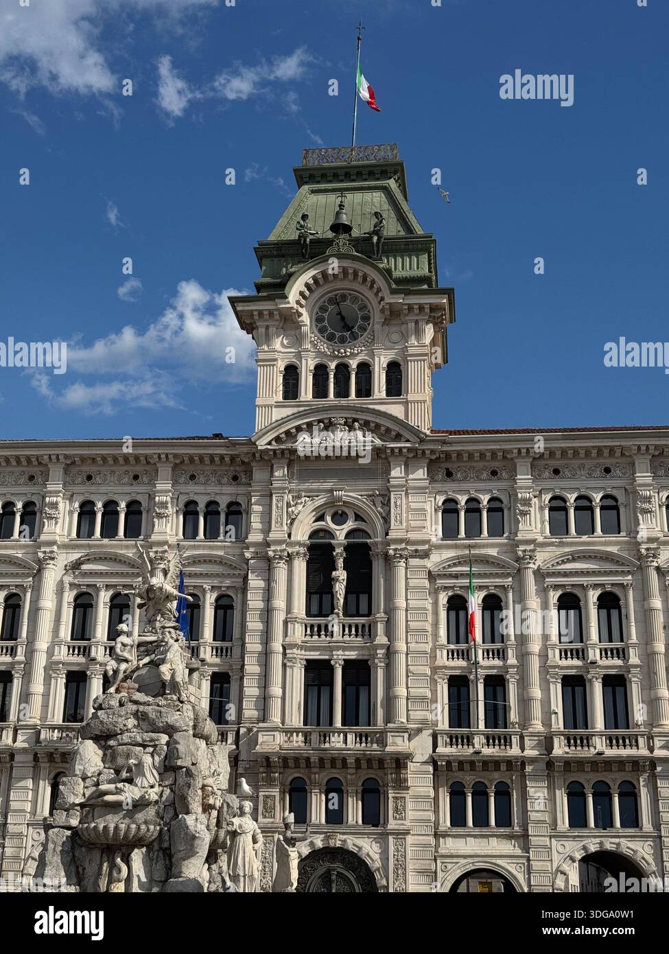 Il Municipio di Trieste, in Italia, sorge con orgoglio in Piazza Unità d'Italia con la sua torre dell'orologio ornata e la fontana scolpita - Immagine stock catturata con smartphone