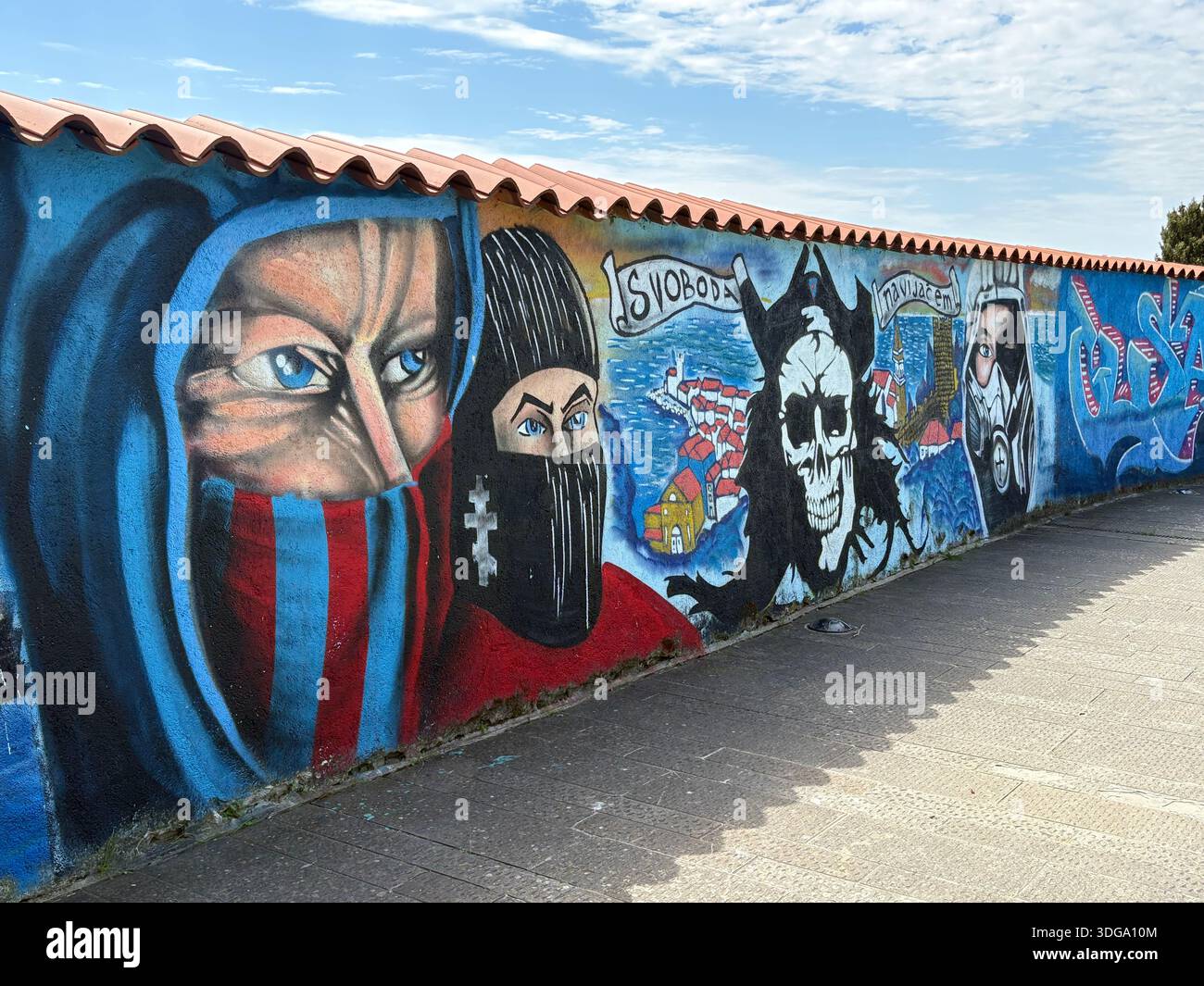 Vivace muro di graffiti con teschi, figure mascherate e slogan nella città costiera, Slovenia Foto Stock