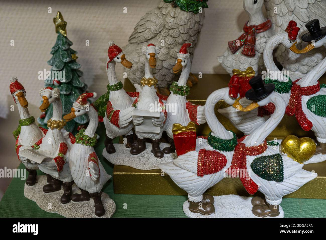 Un gruppo di figurine d'oca decorative che indossano abiti natalizi esposti come parte di una collezione natalizia. Foto Stock