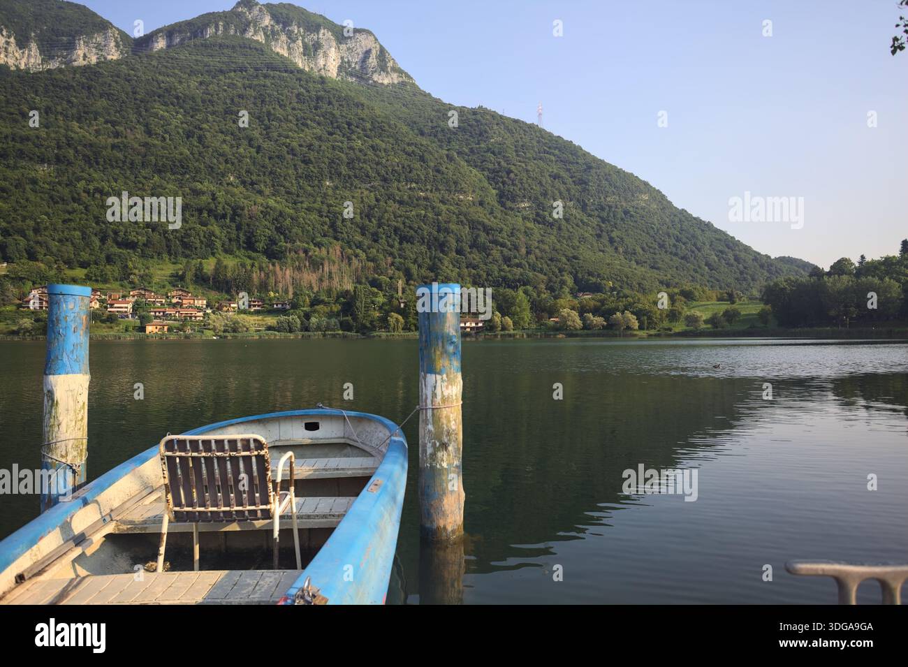 Barca ormeggiata con una sedia vuota su un lago di montagna al tramonto Foto Stock