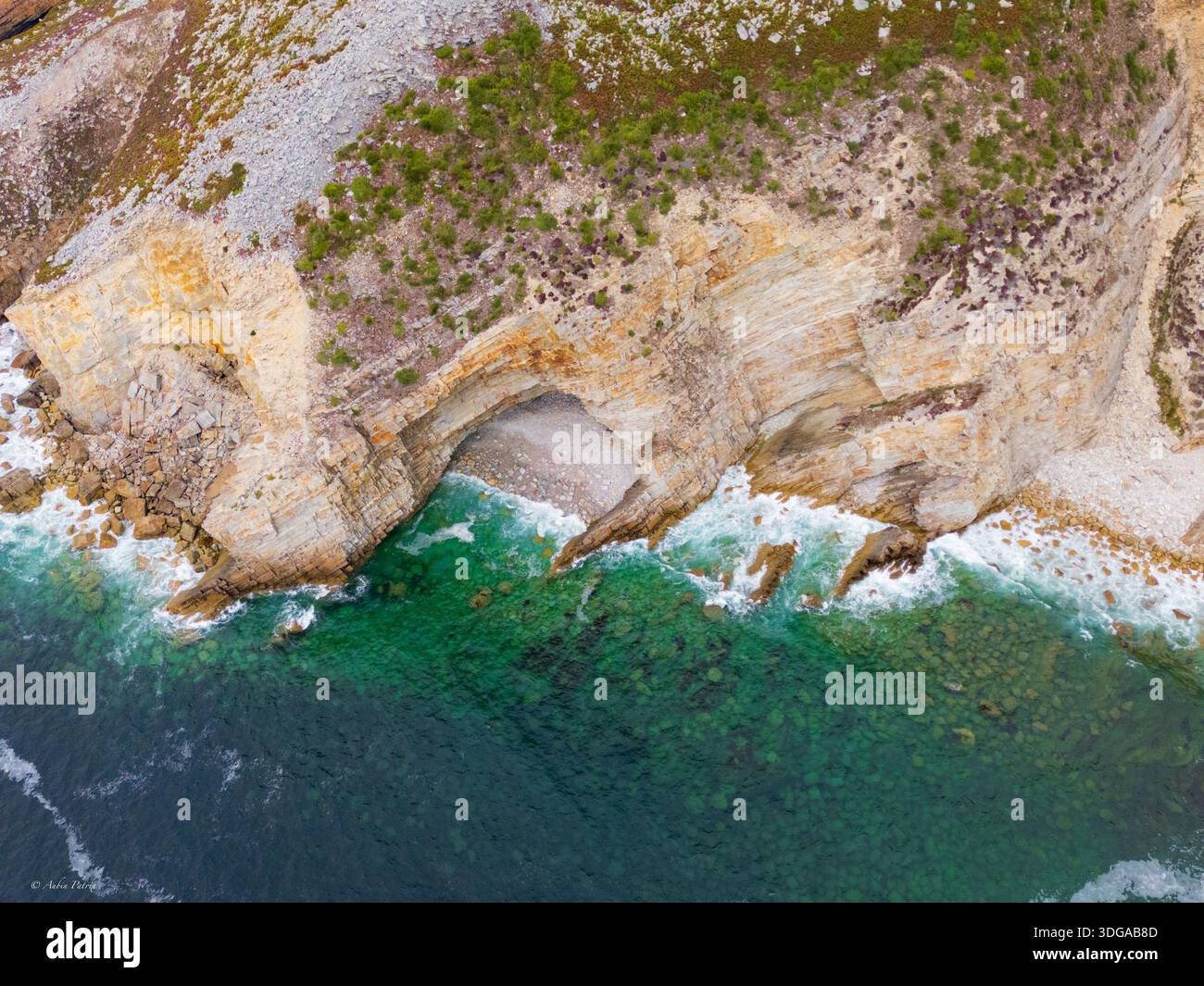 Vista aerea delle aspre scogliere dove le acque turchesi si schiantano contro la costa, rivelando grotte nascoste e affioramenti rocciosi, Santander, Spagna. Foto Stock