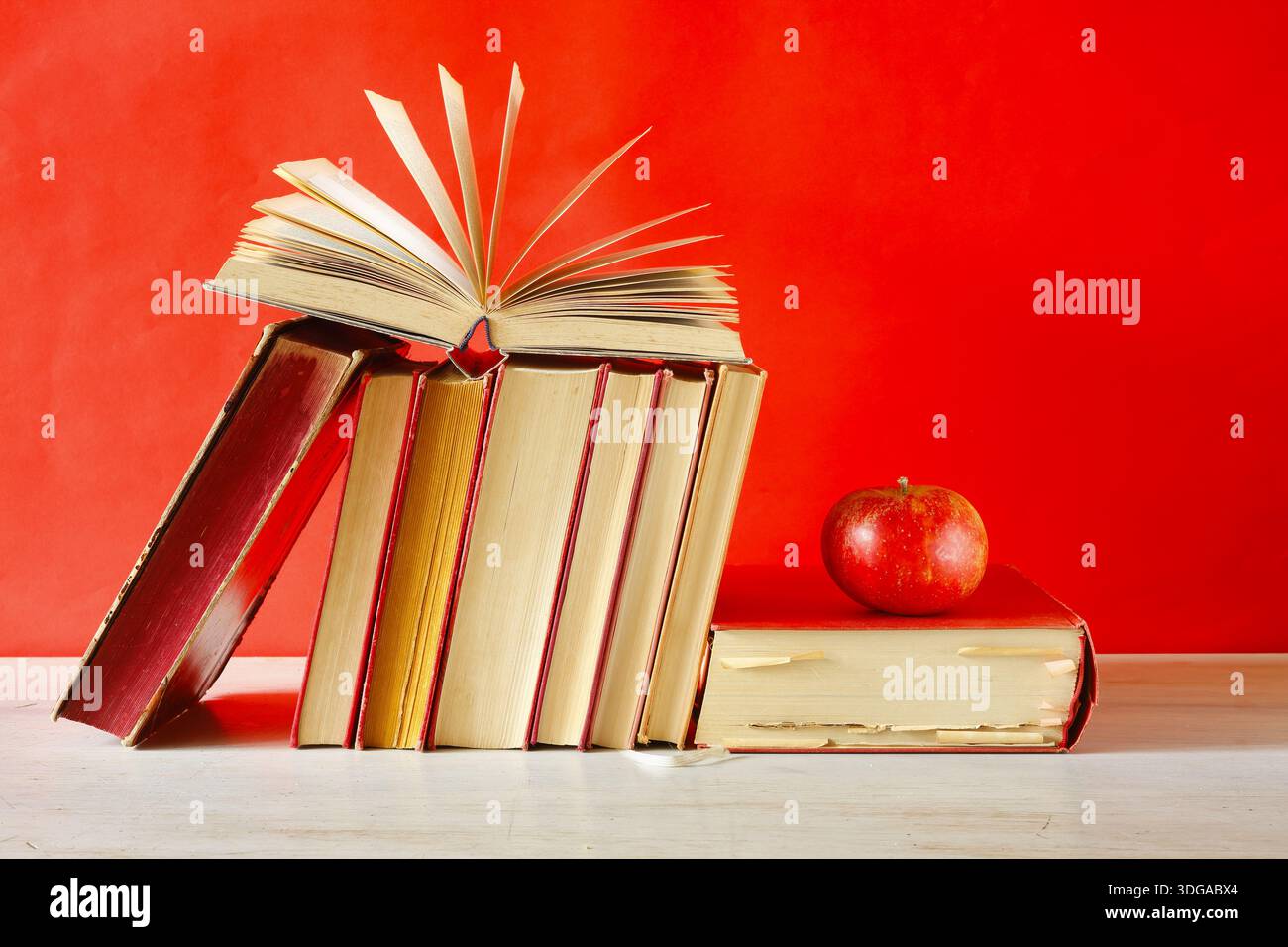 Sistemazione di libri d'epoca. Ritorno a scuola, istruzione, lettura, apprendimento, conoscenza è concetto di potere con libro aperto, una mela e spettacoli. Foto Stock