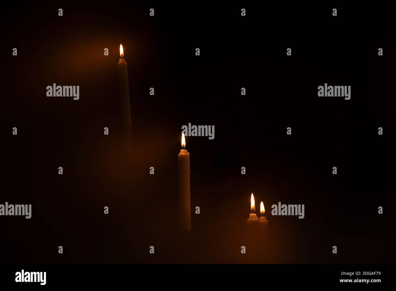 Le candele accese si illuminano al buio con una luce ambientale calda Foto Stock
