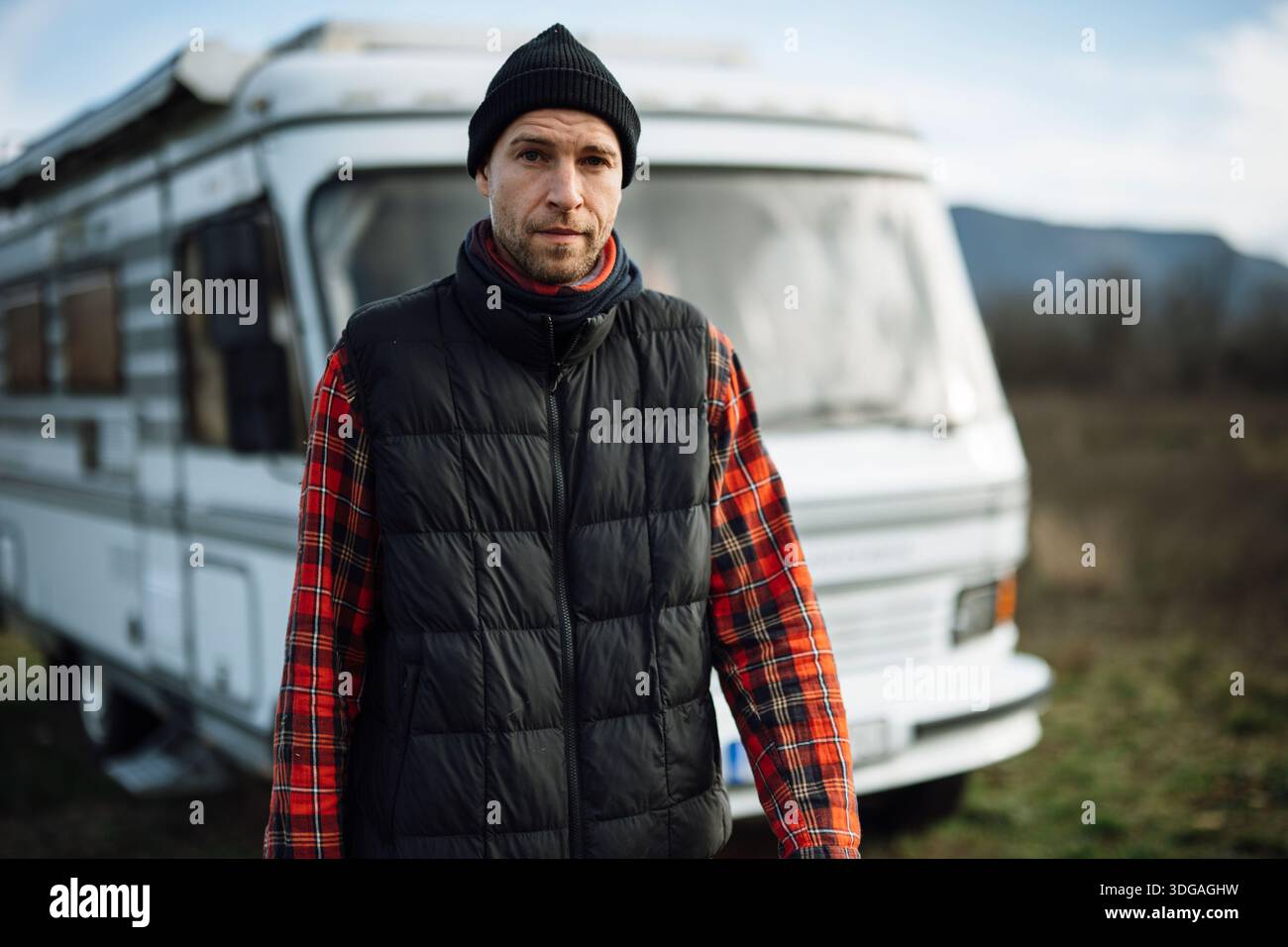 L'uomo si trova di fronte al camper e indossa una camicia a quadri Foto Stock