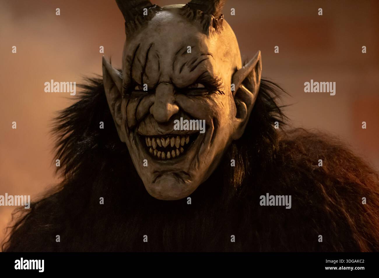 Primo piano ritratto del personaggio di Krampus con corna e rullino aggressivo sotto la calda illuminazione serale Foto Stock