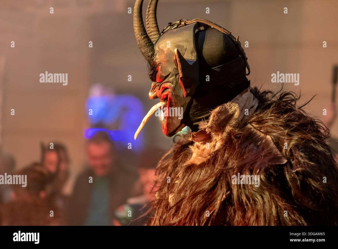 Vista del profilo di Krampus con la lingua fuori e denti affilati durante un festival serale Foto Stock