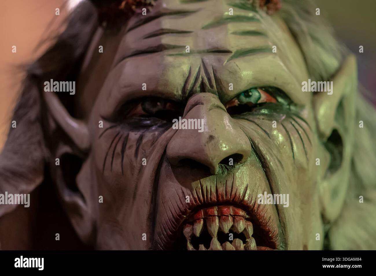 Primo piano estremo di una maschera Krampus con viso rugoso, denti ruvidi e illuminazione laterale dura Foto Stock
