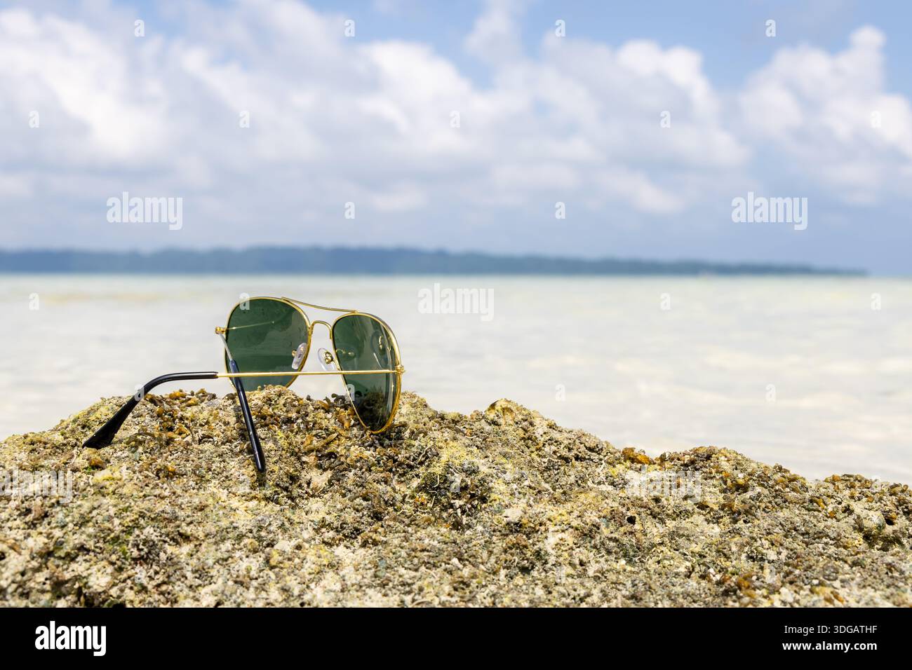scena di viaggio estiva con occhiali da sole su roccia sulla spiaggia Foto Stock