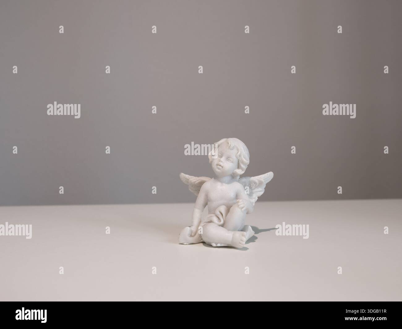 Statuetta angelica in ceramica bianca su sfondo bianco per il design. Fede, simboli e tradizioni. Foto Stock
