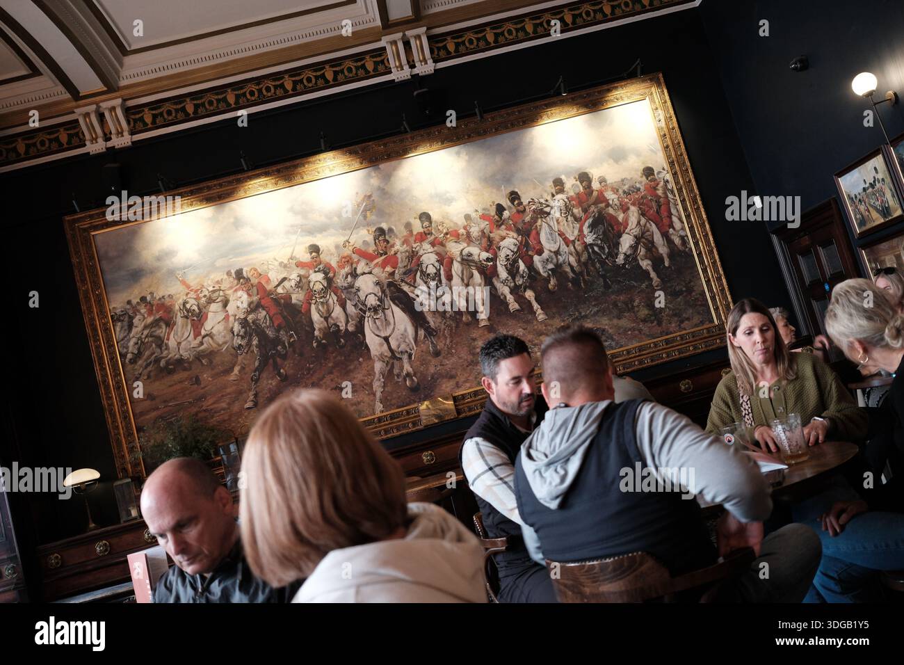 Interno del pub Horse and Guardsman a Whitehall, Londra, con dipinti storici di cavalleria, arredi tradizionali e clienti seduti all'interno. Foto Stock