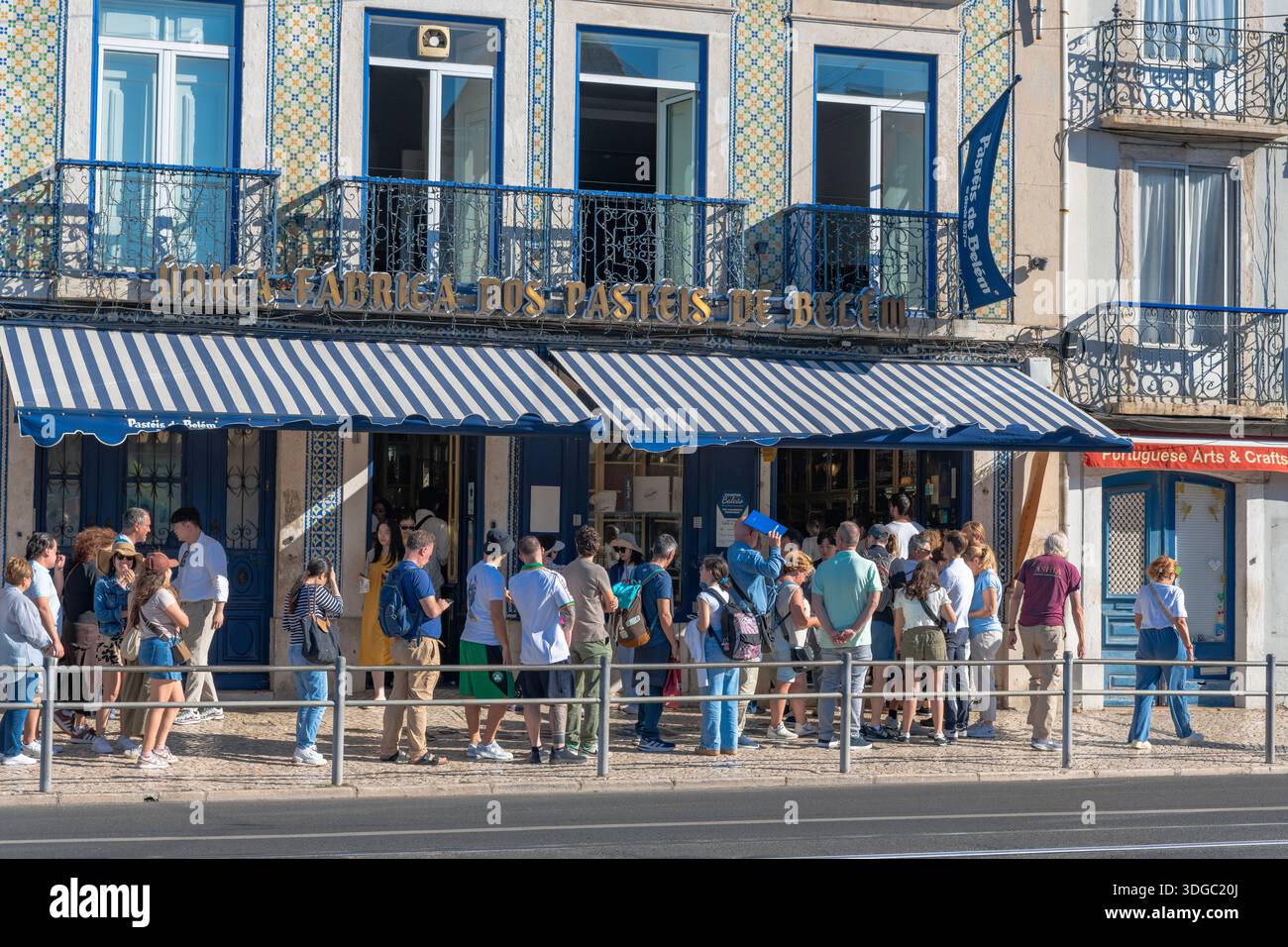 Lisbona, Portogallo - 11 ottobre 2025: Folla di turisti che fanno la fila fuori dalla famosa pasticceria Pastéis de Belém per acquistare le tradizionali crostate portoghesi alla crema pasticcera. Foto Stock