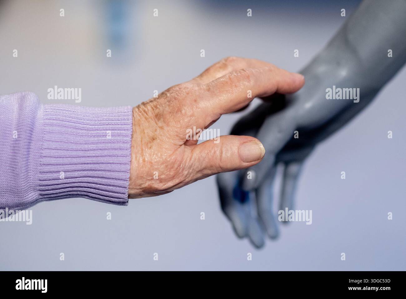 Leer, Germania. 14 gennaio 2026. Un cittadino anziano tocca il robot umanoide "Ameca", la cui mano è fatta di silicone, durante uno spettacolo presso la casa di riposo e di riposo di Haus Friede. Il robot è stato sviluppato dalla società britannica Engineered Arts e può essere programmato in diversi modi. Gli scienziati dell'OFFIS Institute for Information Technology di Oldenburg stanno attualmente studiando l'interazione tra esseri umani e macchine nelle case di cura nel nord-ovest. Crediti: Hauke-Christian Dittrich/dpa/Alamy Live News Foto Stock