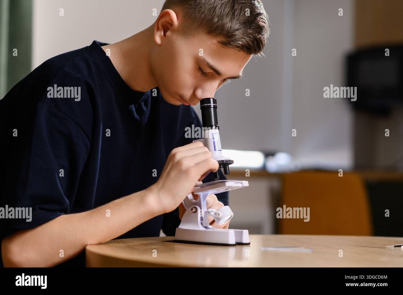 L'adolescente esamina i vetrini di vetro al microscopio in preparazione al seminario. Lo studente conduce l'osservazione biologica per il progetto scolastico Foto Stock