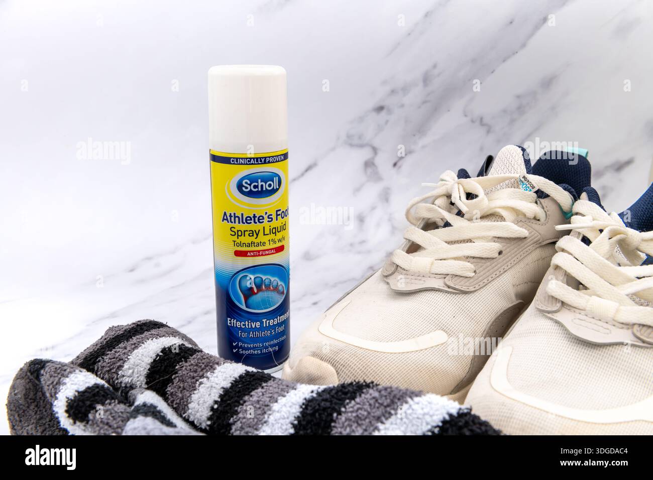Londra. Regno Unito - 14 gennaio 2026. Un contenitore di liquido spray per piedi Scholl Athlete, insieme a un paio di calzini e scarpe da running isolate su un mar bianco Foto Stock