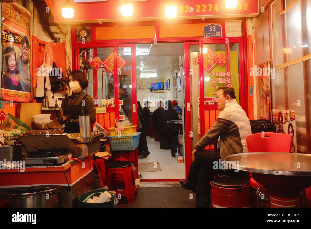 Seoul, Corea del Sud: Ristorante di strada coreano locale con cucina che prepara cibo e clienti seduti all'interno di un piccolo locale tradizionale Foto Stock