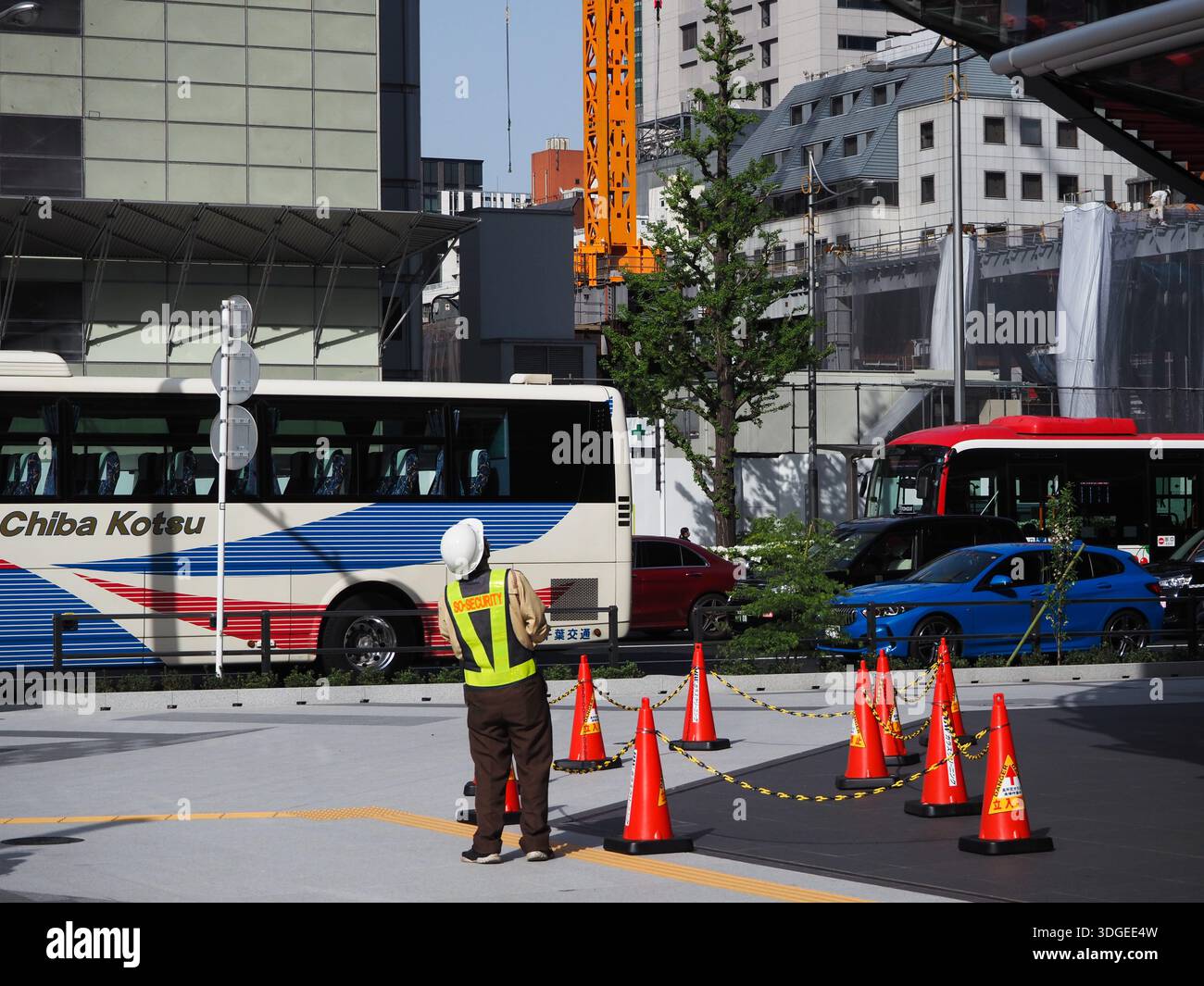 TOKYO, GIAPPONE - 11 aprile 2023: Operaio davanti a Yanmar Tokyo sotto i lavoratori in una culla che stanno pulendo l'edificio. Foto Stock