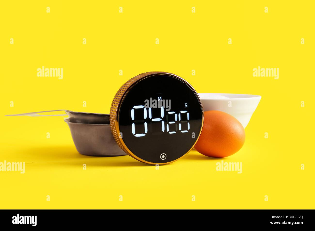 Moderno timer da cucina, paletta, recipiente e uovo su sfondo giallo Foto Stock
