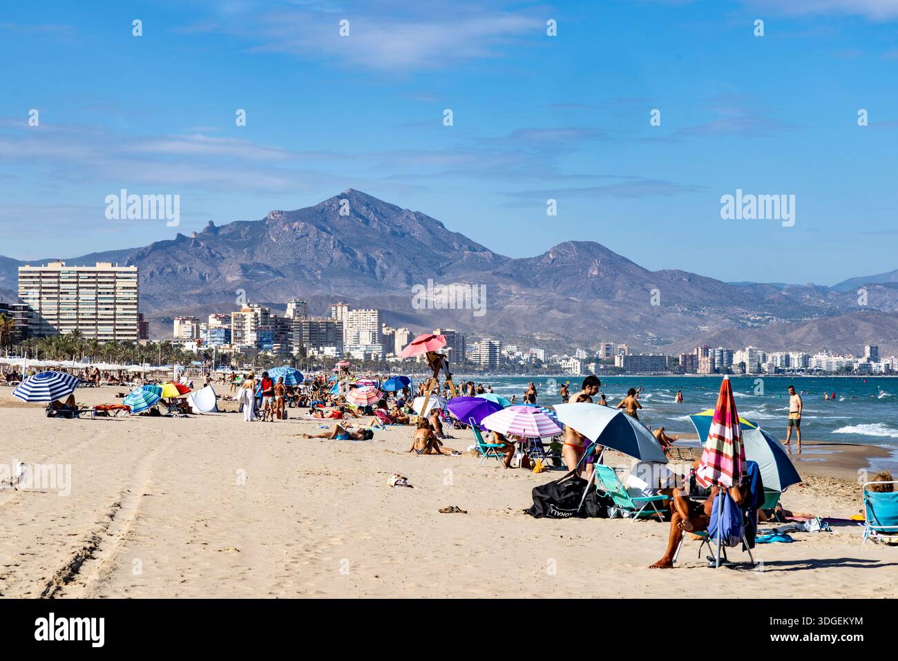 Spiaggia di Alicante, Spagna, spiaggia Playa de San Juan su cielo blu giorno d'autunno con persone che si rilassano e prendono il sole accanto al Mar Mediterraneo , Europa,2025 Foto Stock