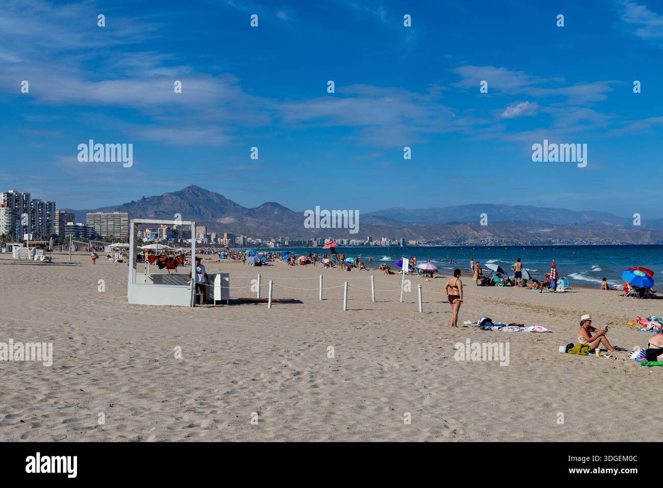 Spiaggia di Alicante, Spagna, spiaggia Playa de San Juan su cielo blu giorno d'autunno con persone che si rilassano e prendono il sole accanto al Mar Mediterraneo , Europa,2025 Foto Stock