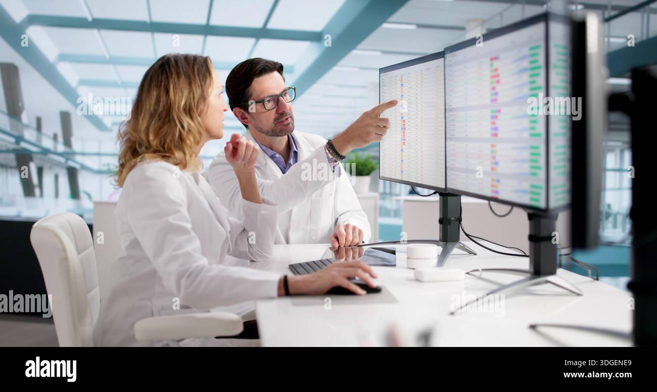 Professionisti medici che lavorano su codici di fatturazione e audit su più monitor. Foto Stock