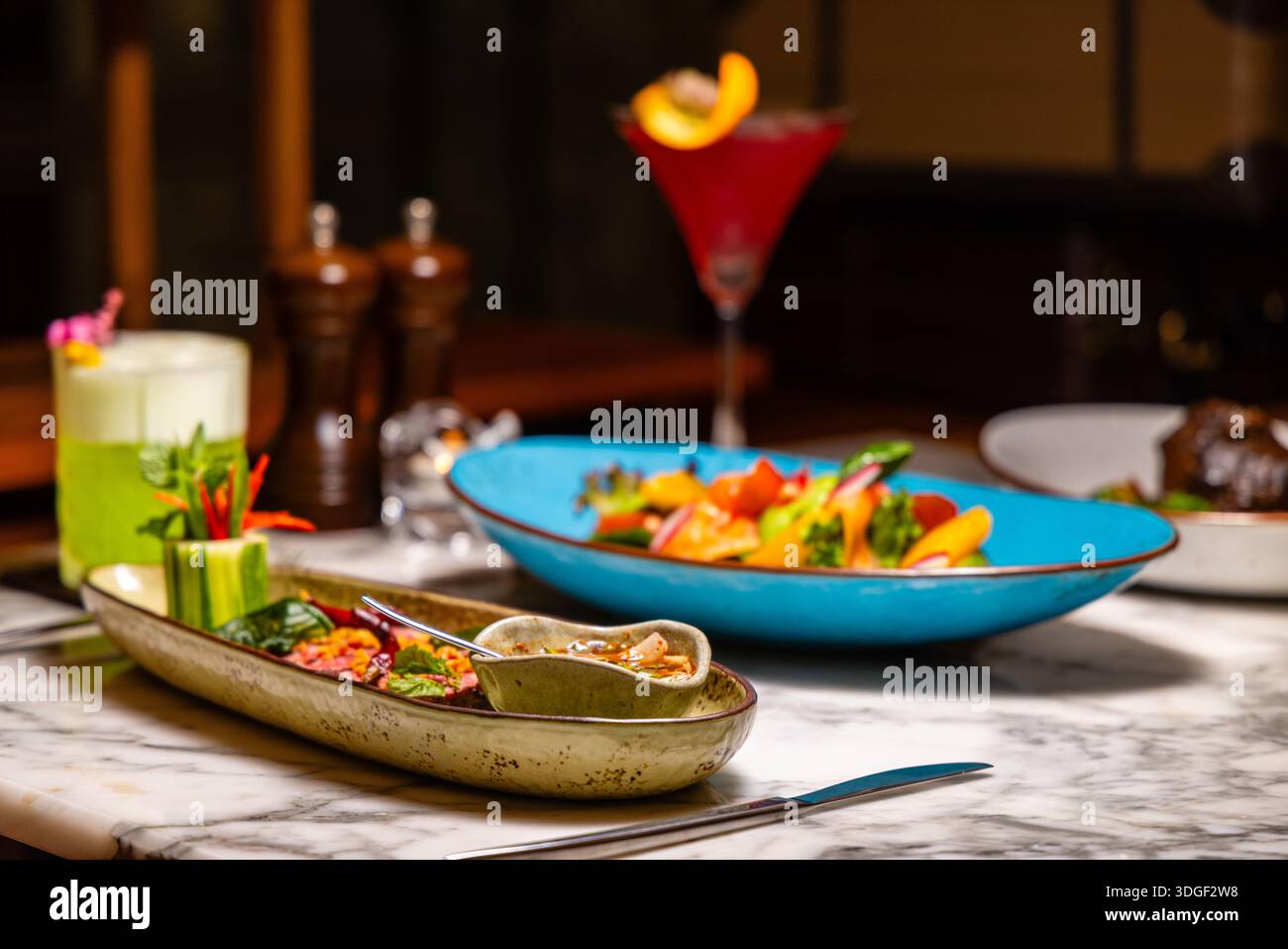 Elegante cucina fusion su tavolo in marmo con vivaci cocktail, Foto Stock