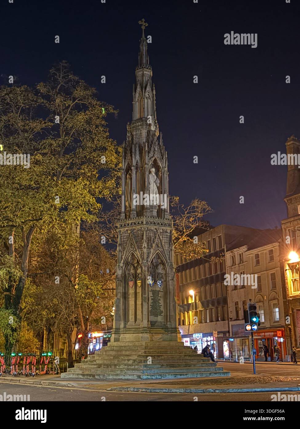 Monumento storico in pietra illuminato in una piazza della città di notte, circondato da alberi ed edifici a Oxford. - Immagine stock catturata con smartphone