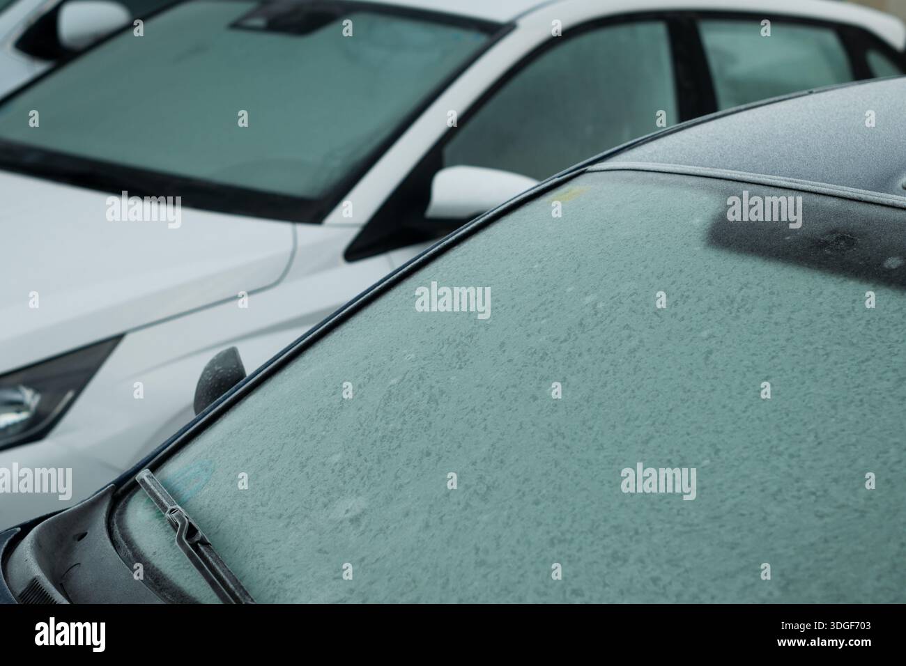 Parabrezza dell'auto ricoperto di ghiaccio e gelo in una fredda mattina, segnalando lo scongelamento primaverile Foto Stock