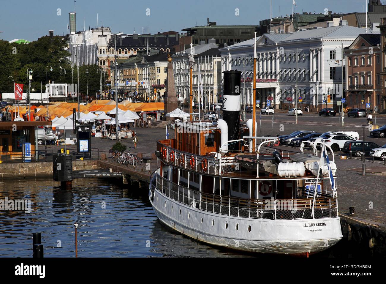 La piazza del mercato di Helsinki con una barca ed edifici storici lungo la trafficata passeggiata del porto, Helsinki, Finlandia Foto Stock