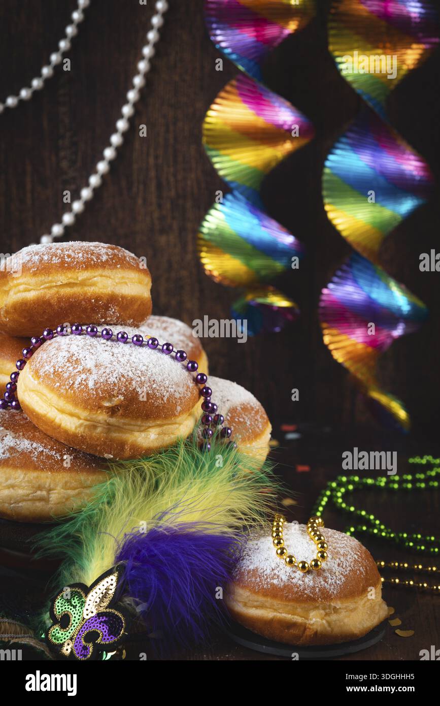Berliner con zucchero a velo, decorato con collane di perle e colorate spirali su sfondo scuro, carnevale Foto Stock