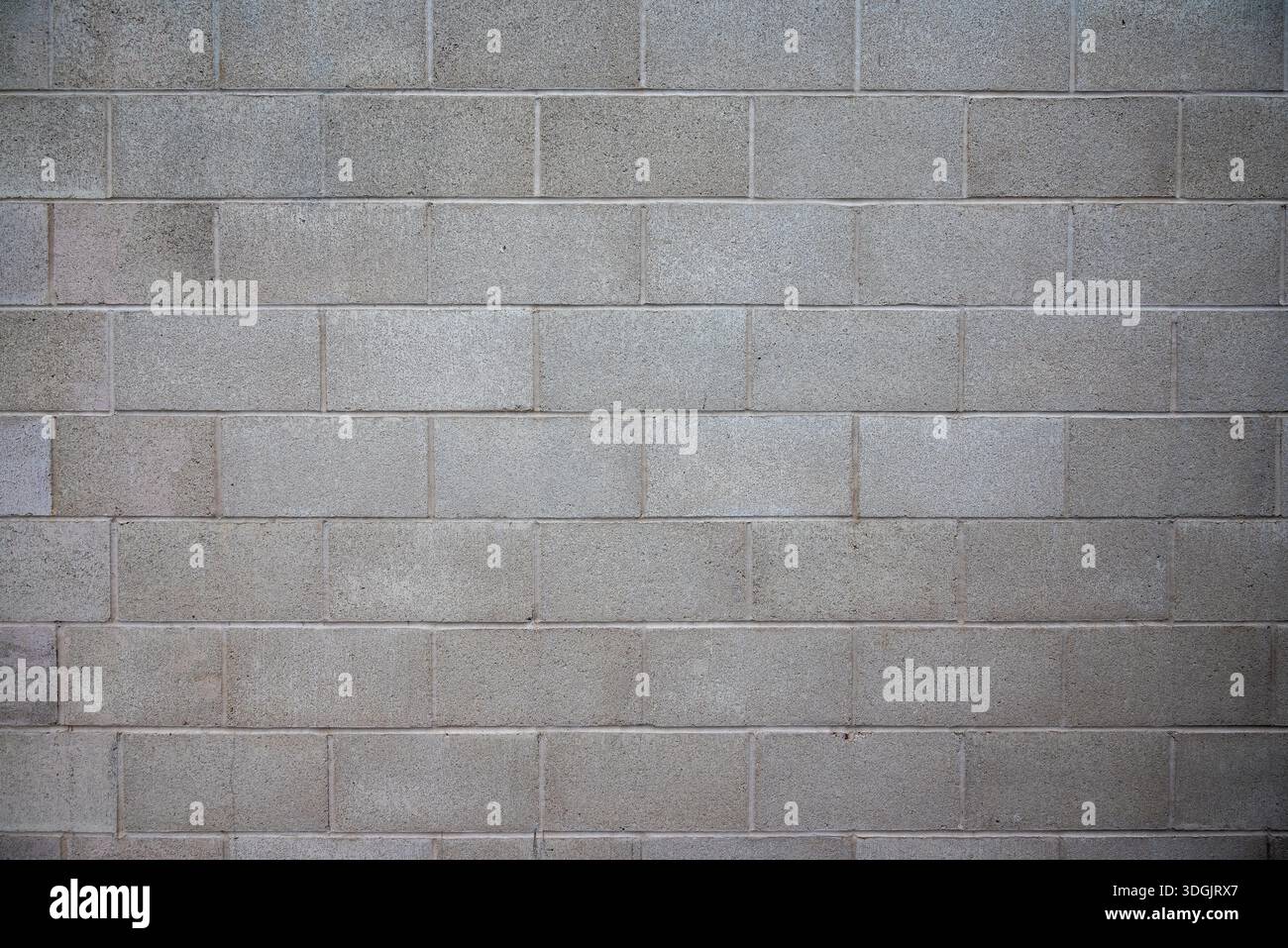 Primo piano di un muro di cemento di scorie grezzo e non verniciato con grandi mattoni uniformi. La texture ruvida e le tonalità neutre sottolineano uno stile minimalista e industriale. Foto Stock