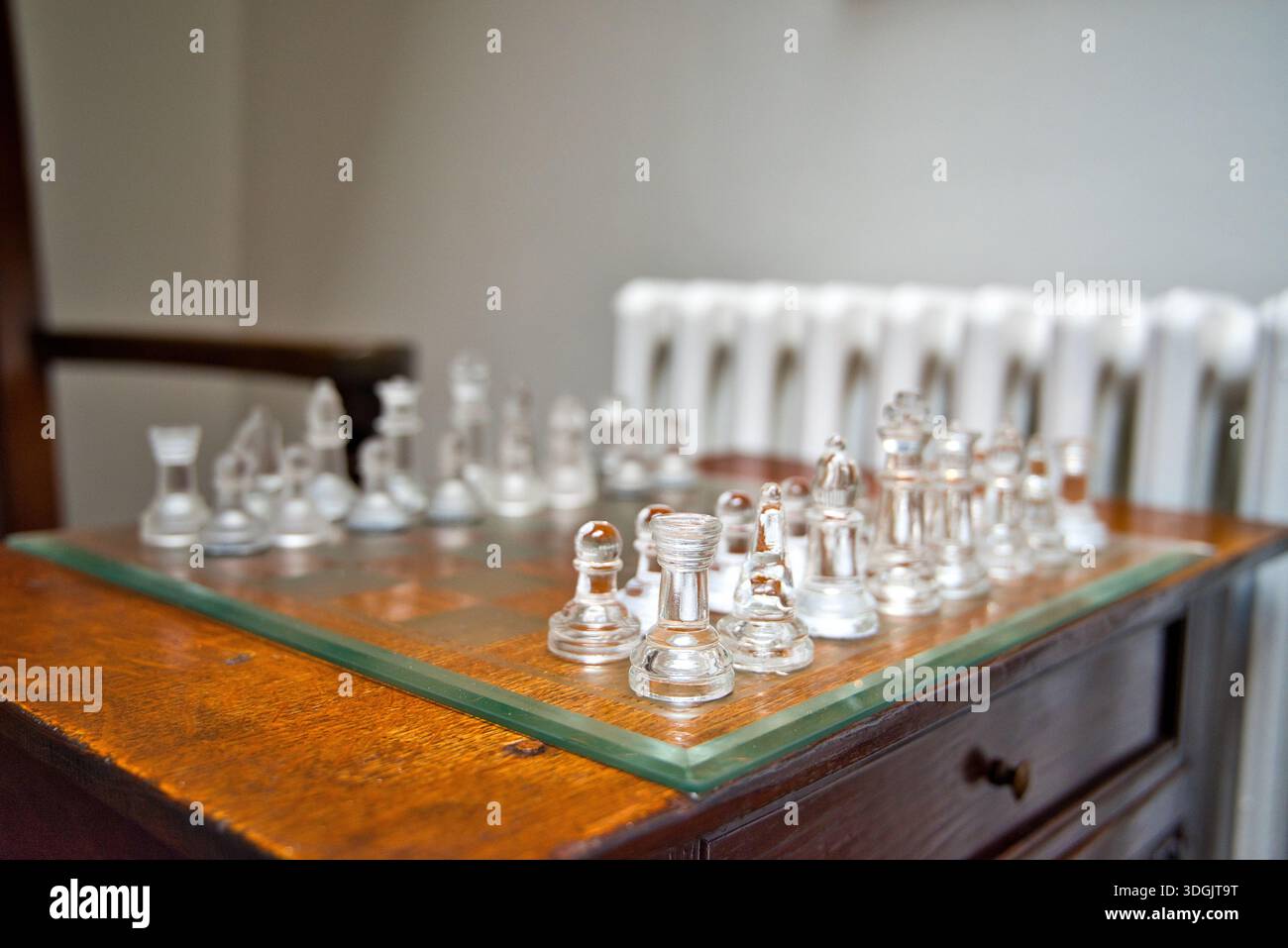 Un bellissimo set di scacchi in vetro disposto su un classico tavolino in legno scuro, che evoca un'atmosfera intima e intellettuale in un tradizionale hotel scozzese. Foto Stock