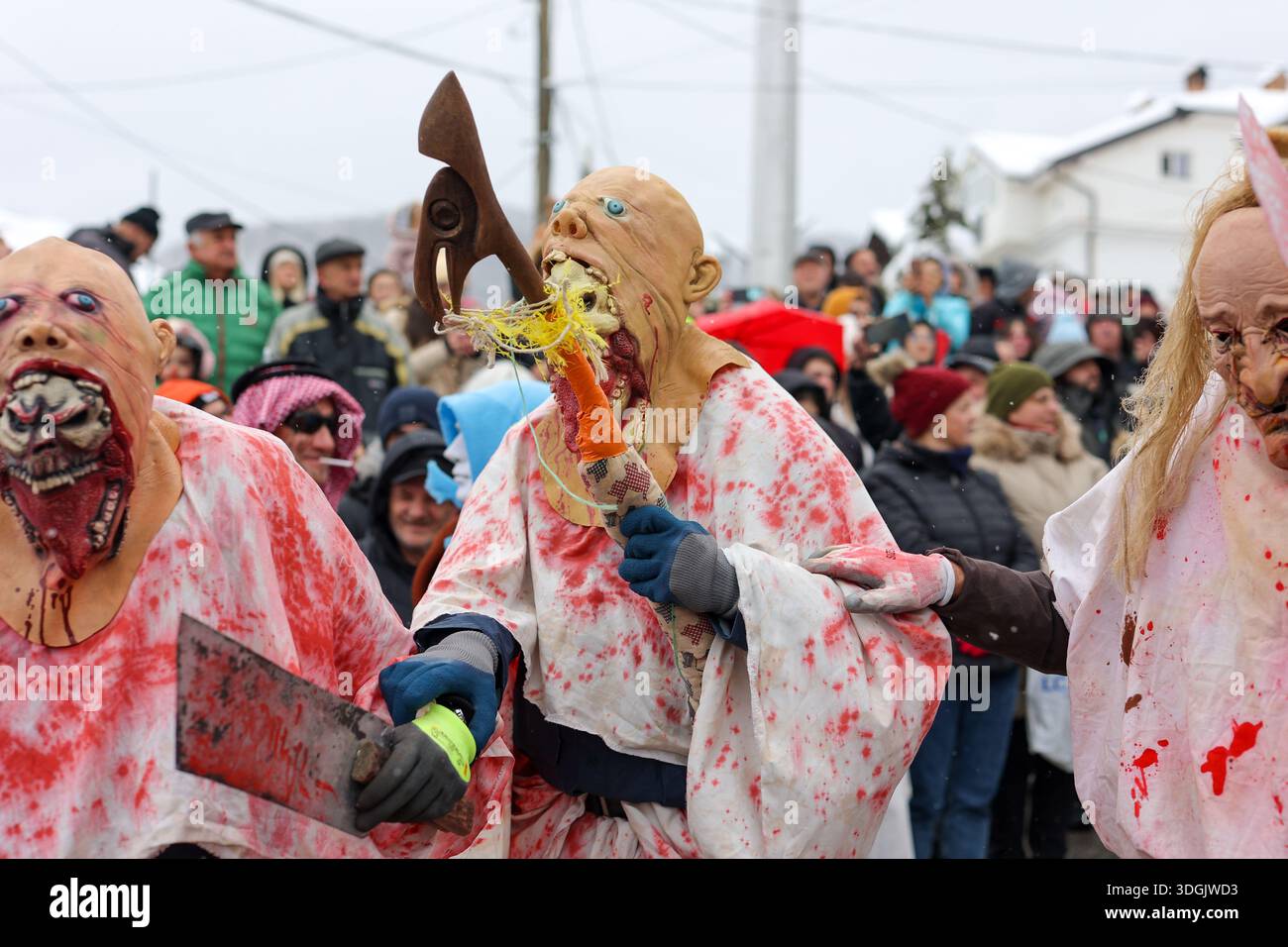 Artisti mascherati grotteschi con asce durante la tradizionale sfilata di carnevale invernale Foto Stock