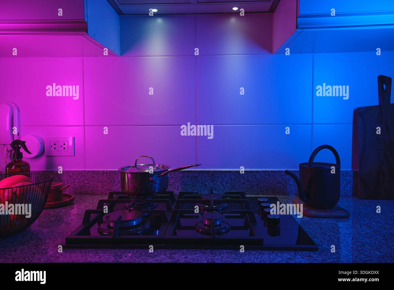 Gli interni della cucina presentano una stufa e un bancone illuminati da vivaci luci LED rosa e blu Foto Stock