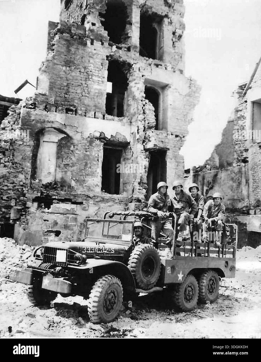 Soldati AMERICANI su un camion Dodge WC63 nelle rioni di Trevières dopo il D-Day. Trevières si trova a pochi chilometri dalla spiaggia ed è stata pesantemente danneggiata dall'assalto. Il 6 giugno 1944 un'enorme forza d'invasione Alllied che coinvolgeva 7000 navi e 140.000 uomini sbarcò con successo sulla costa francese e stabilì cinque teste di spiaggia. Una campagna di inganno di successo significò che gran parte della resistenza tedesca si trovava a Calais e le perdite furono relativamente poche per le dimensioni e i rischi dell'operazione. Foto Stock