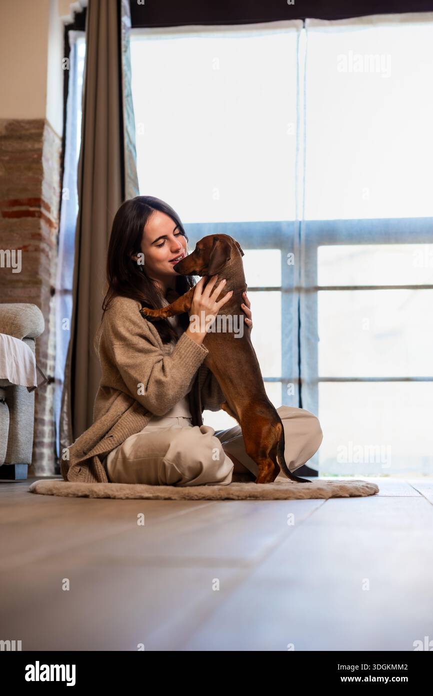 Donna che si lega con il dachshund a casa Foto Stock