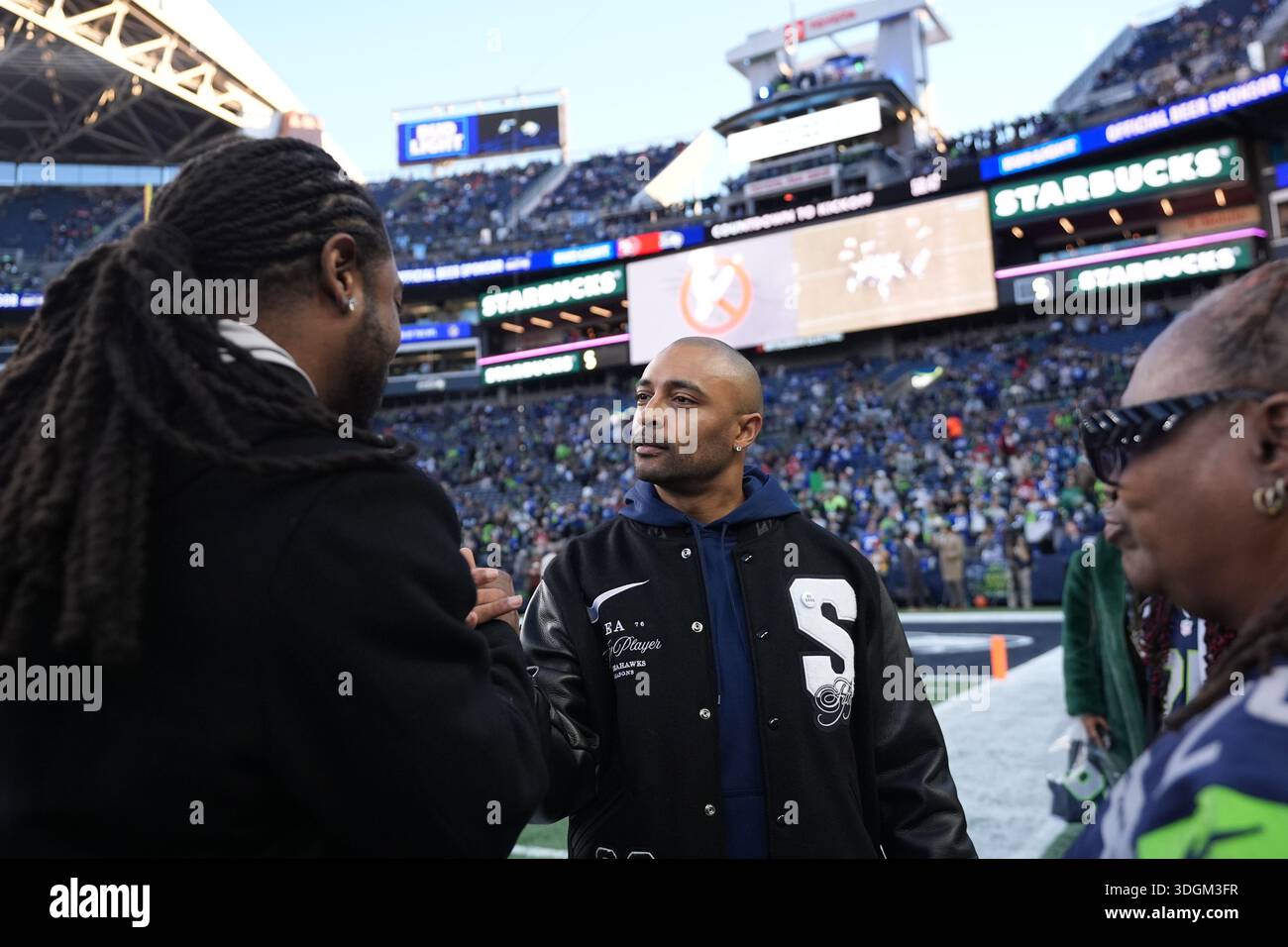 Former NFL player Doug Baldwin, second from left, greets former NFL player Richard Sherman before an NFL football divisional playoff game between the Seattle Seahawks and the San Francisco 49ers, Friday, Jan. 17, 2025, in Seattle. (AP Photo/Lindsey Wasson) Foto Stock