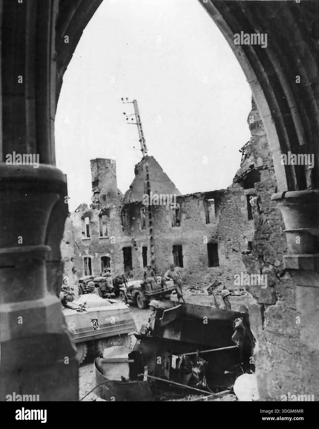 Truppe STATUNITENSI nel villaggio danneggiato di St Giles dopo il D-Day. Il 6 giugno 1944 un'enorme forza d'invasione Alllied che coinvolgeva 7000 navi e 140.000 uomini sbarcò con successo sulla costa francese e stabilì cinque teste di spiaggia. Una campagna di inganno di successo significò che gran parte della resistenza tedesca si trovava a Calais e le perdite furono relativamente poche per le dimensioni e i rischi dell'operazione. Foto Stock