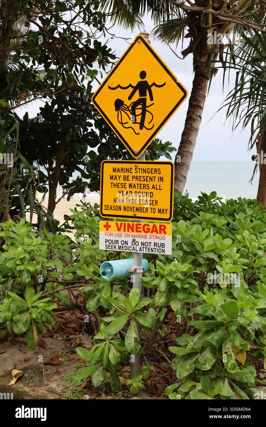 Insegna di sicurezza Marine Stingers e bottiglia di aceto circondati da palme e piante tropicali in una spiaggia Foto Stock