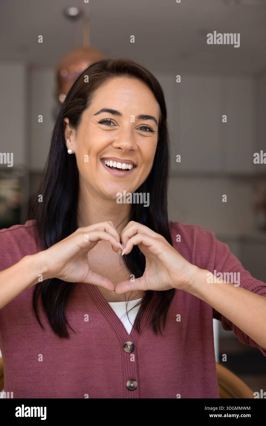 Attraente donna latina bruna anni '40 che mostra gesto cardiaco con le mani Foto Stock