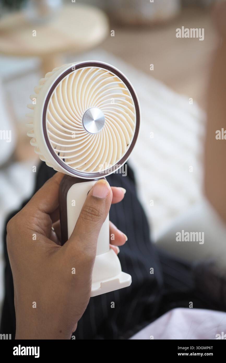 Il ventilatore portatile viene utilizzato in ambienti interni in una giornata calda Foto Stock