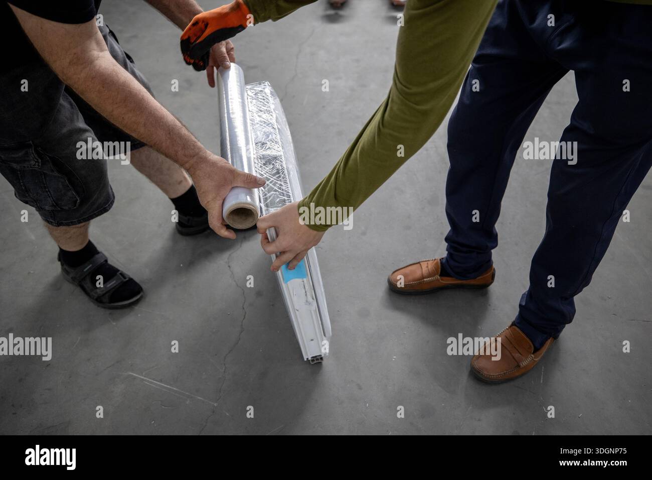 Area di produzione per finestre in metallo-plastica o PVC, comunemente nota come finestra in vinile. Due operatori che confezionano una finestra di plastica, fissando l'involucro protettivo Foto Stock