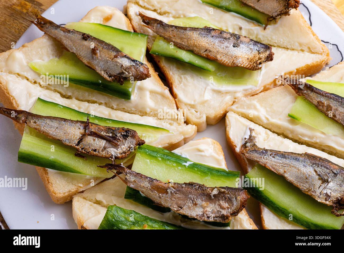 Classici panini a vista con spratti e fette di cetriolo, semplici spuntini di pesce. Foto Stock